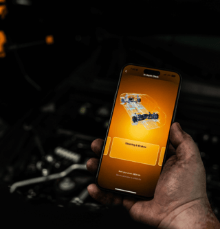 Male auto technician using the GWSCAN app on his smartphone to diagnose issues with a vehicle