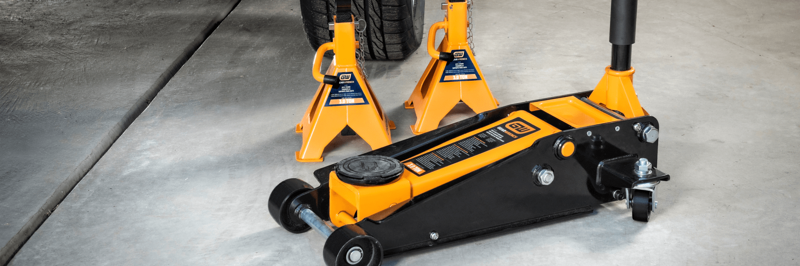 GEARWRENCH jack stands and floor jacks sitting in front of a car in a garage