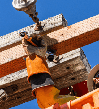 Utility worker in an aerial bucket using a GEARWRENCH ratcheting wrench to fasten hardware on a wooden utility pole crossarm.