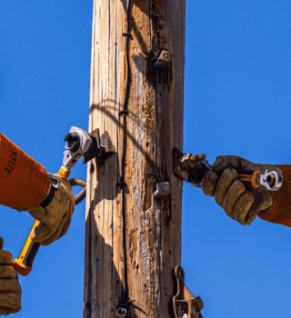 Utility workers using GEARWRENCH insulated ratcheting wrenches to tighten hardware on a wooden utility pole from elevated bucket trucks.