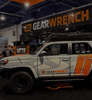 Wide view of the GEARWRENCH booth at SEMA showcasing a customized off-road vehicle, tool displays, product demonstrations, and attendees exploring the exhibit.
