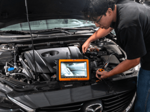 Man using the GWSMART10 and GWSCOPE to inspect an issue in an engine bay of a Mazda vehicle
