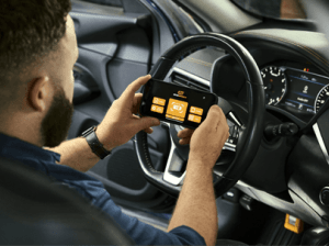 Male mechanic using the GWSMARTBT bi-directional scan tool and his smartphone to diagnose issues with a vehicle