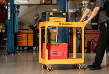 Male mechanic pushing the GEARWRENCH 2-shelf automotive cart through an auto shop