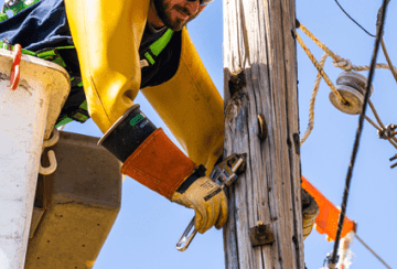 Lineman using a lineman adjustable wrench on a utility pole hardware