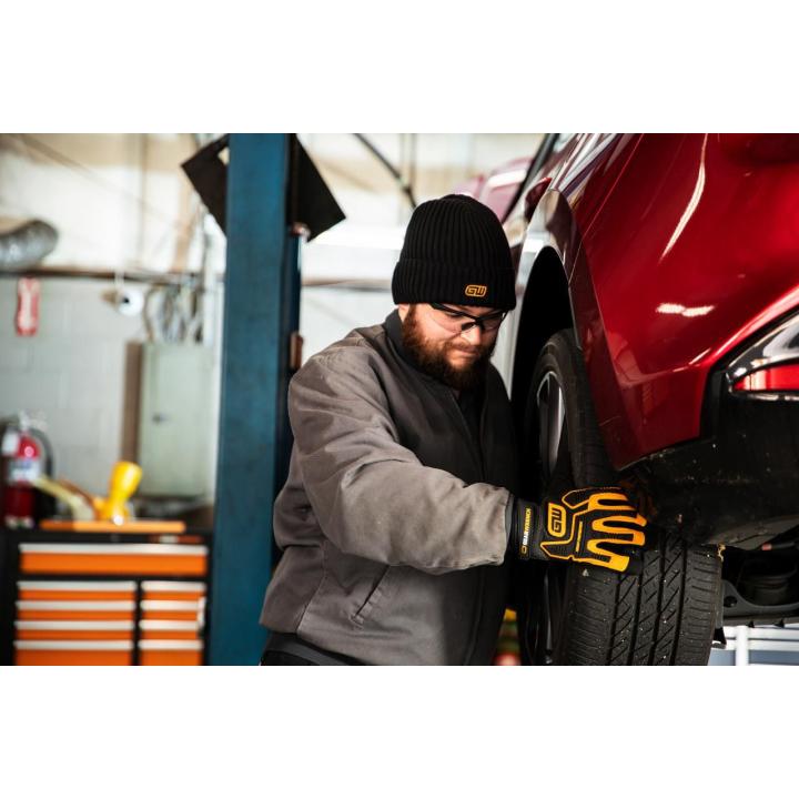 Image of the  Knitted Cuffed Beanie - Black with a person wearing the beanie installing a tire
