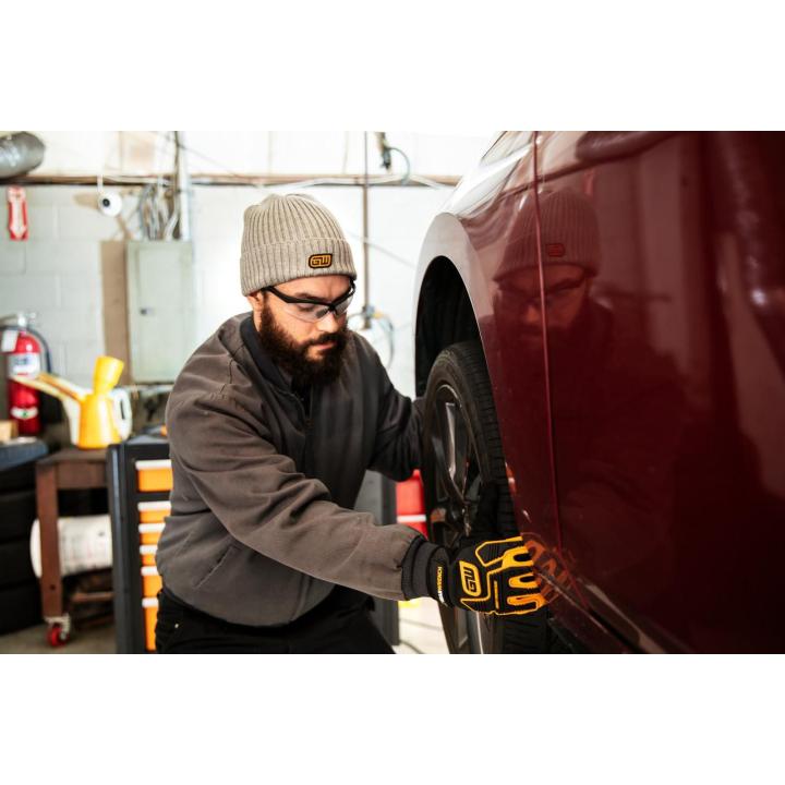 Image of the  Knitted Cuffed Beanie - Grey with a person wearing the beanie installing a tire
