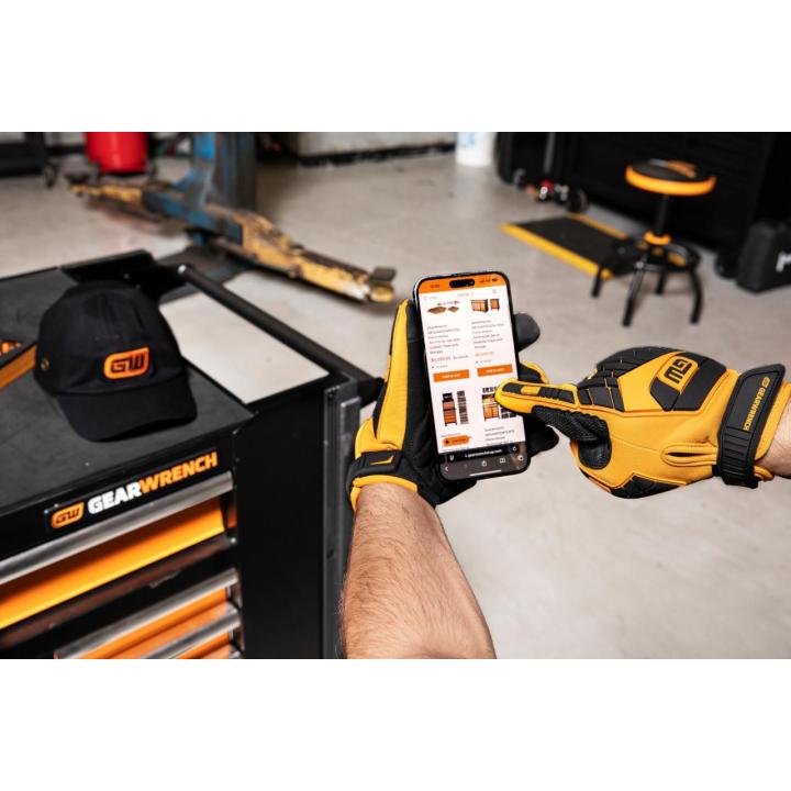 Man using a cell phone while wearing GWSGMM1 gloves in a shop setting