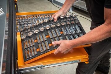 Man placing GEARWRENCH chrome socket modular set into an orange tool drawer