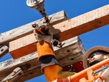 Utility worker in an aerial bucket using a GEARWRENCH ratcheting wrench to fasten hardware on a wooden utility pole crossarm.
