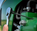 Male farmer using GEARWRENCH 90T ratchet to tighten a bolt on a green tractor